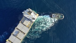 Aerial Drone Top Down Photo Of Tow - Tug Boat Assisting By Pulling Empty Container Ship To Depart From Container Terminal Port