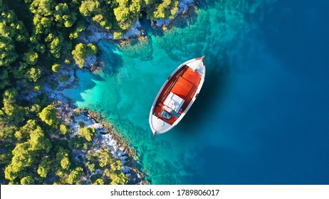 Aerial drone top down photo of traditional fishing boat anchored near small picturesque port of Agnontas, Skopelos, Sporades, Greece - Powered by Shutterstock
