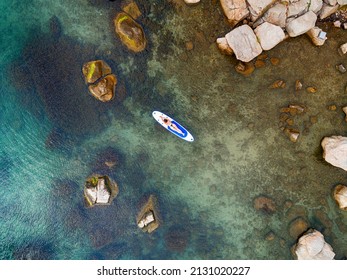 Aerial drone top down photo of unidentified woman exercising in SUP or Stand Up Paddle board in exotic  beach
