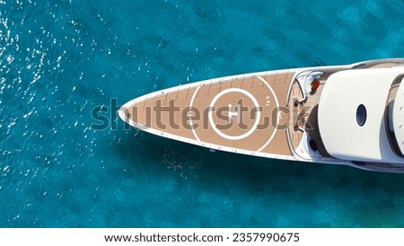 Aerial drone top down photo of luxury yacht nose with wooden deck and helipad anchored in paradise exotic turquoise island bay