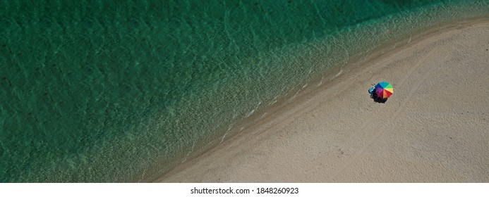 Aerial Drone Top Down Ultra Wide Photo Of Secluded Paradise Sandy Turquoise Beach With Only One Orange Sun Umbrella