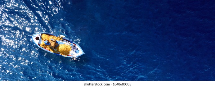 Aerial drone top down ultra wide photo of traditional wooden fishing boat docked near port of Mykonos island, Cyclades, Greece