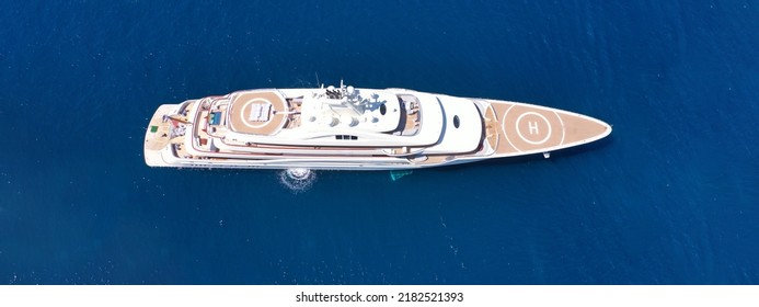 Aerial Drone Top Down Ultra Wide Photo With Copy Space Of Luxury Mega Yacht With Wooden Deck And Helipad Anchored In Deep Blue Aegean Sea