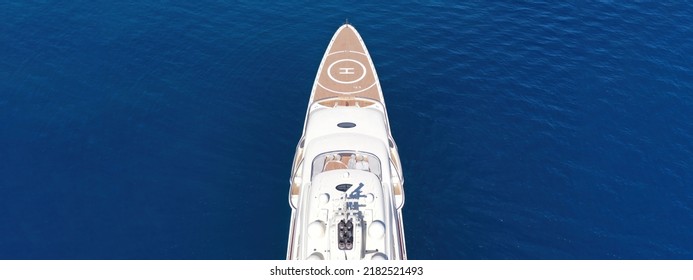 Aerial Drone Top Down Ultra Wide Photo With Copy Space Of Luxury Mega Yacht Nose With Wooden Deck And Helipad Anchored In Deep Blue Aegean Sea