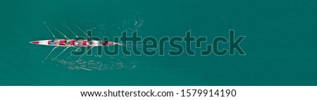 Aerial drone top down ultra wide panoramic view of sport canoe rowing synchronous athletes competing in tropical exotic lake