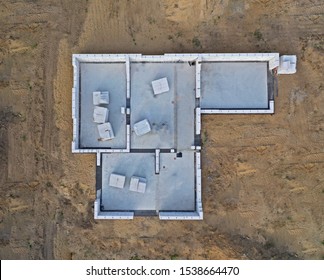 Aerial Drone Top Down View On Construction Site With Reinforced Concrete House Foundation, Poured Concrete Floor And Brick Walls.