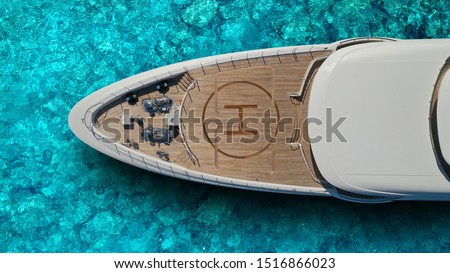 Aerial drone top view photo of large yacht - boat with helicopter landing area anchored in tropical exotic paradise bay with turquoise open sea
