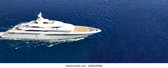 Aerial Drone Ultra Wide Panoramic Photo Of Beautiful Modern Super Yacht With Wooden Deck Cruising In High Speed Deep Blue Open Ocean Sea