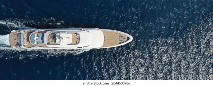 Aerial Drone Ultra Wide Panoramic Photo Of Beautiful Modern Super Yacht With Wooden Deck Cruising In High Speed Deep Blue Open Ocean Sea