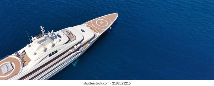 Aerial Drone Ultra Wide Panoramic Photo With Copy Space Of Mega Luxurious Yacht With Wooden Deck Anchored In Aegean Island Deep Blue Sea