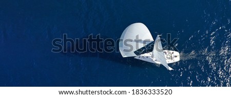Aerial drone ultra wide panoramic photo with copy space of beautiful sail boat with white sails cruising deep blue sea near Mediterranean destination port