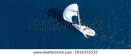 Aerial drone ultra wide panoramic photo of beautiful sailboat with white sails cruising deep blue sea near Mediterranean destination port