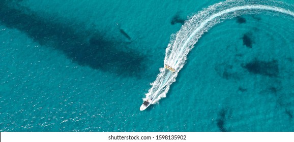 Aerial drone ultra wide photo of group of young women practising in donut water-sports in turquoise clear sea beach in exotic destination