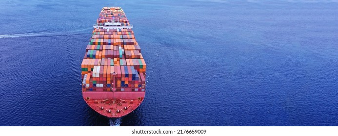 Aerial Drone Ultra Wide Photo Of Bow From Huge Fully Loaded Container Tanker Ship Carrying Truck Size Colourful Containers In Deep Blue Open Ocean Sea