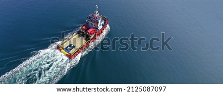 Aerial drone ultra wide photo of industrial tug assisting vessel cruising near container terminal port