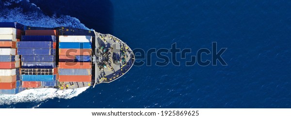 Aerial drone ultra wide photo\
with copy space of colourful truck size container tanker ship\
cruising deep blue sea near commercial port of Piraeus, Attica,\
Greece
