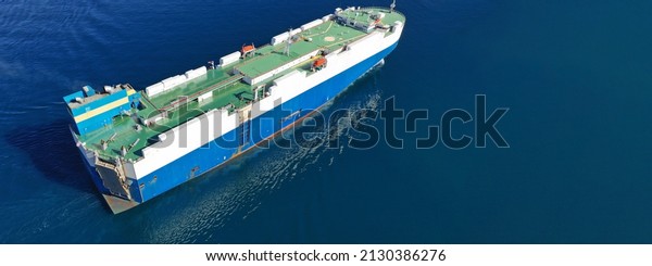 Aerial drone ultra wide photo of huge car carrier\
ship RO-RO (Roll on Roll off) cruising in Mediterranean deep blue\
Aegean sea