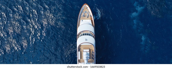Aerial drone ultra wide top down photo of luxury yacht with wooden deck anchored in Aegean island with deep blue sea, Greece