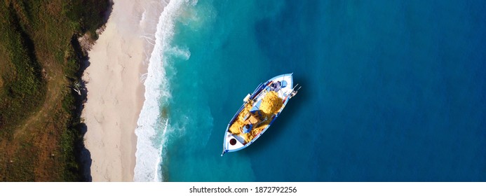 Aerial drone ultra wide top view photo of red wooden traditional fishing boat in turquoise sea shore of Zakynthos island, Ionian, Greece