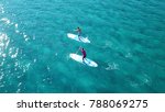 Aerial drone view of 2 men exercising sup board in turquoise tropical clear open sea