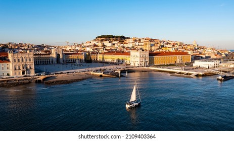 Aerial drone view of the Augusta Street Arch from Commerce Square in Lisbon, Portugal. Winter sunset and a boat in tagus river.