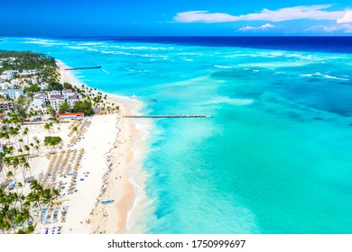 Aerial Drone View Of Beautiful Atlantic Tropical Beach With Palms, Straw Umbrellas And Boats. Bavaro, Punta Cana, Dominican Republic. Vacation Background