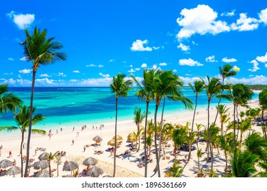 Aerial drone view of beautiful atlantic tropical beach with palms, straw umbrellas and boats. Bavaro, Punta Cana, Dominican Republic. Vacation background