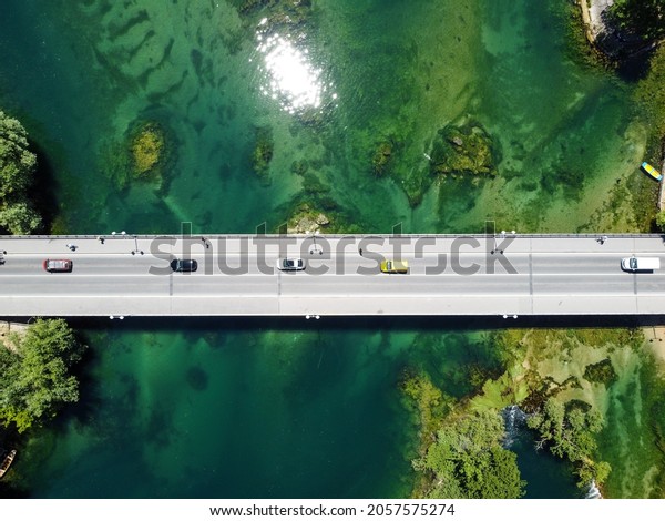Aerial drone view\
of bridge above beautiful green river. Cars and pedestrians moving\
on bridge, view from above. Transportation. Modern concrete bridge\
over the lake.