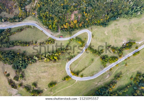 Aerial\
drone view of curving road in autumn\
countryside.