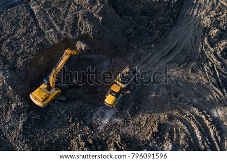 Aerial drone view of excavator loading the tipper truck at the construction site