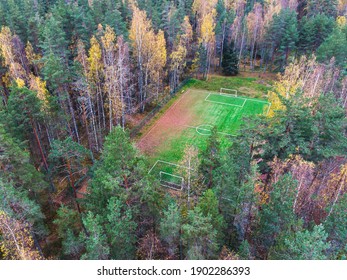 Aerial Drone View Of Football Soccer Pitch Field, Green Grass Fall Autumn Vibrant Pitch Playground With Fallen Multicolored Leaves In The Forest, Hidden In The Woods