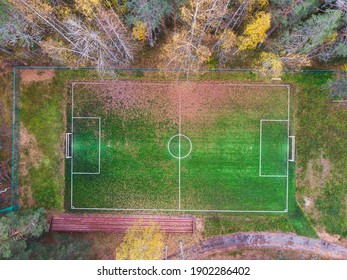 Aerial Drone View Of Football Soccer Pitch Field, Green Grass Fall Autumn Vibrant Pitch Playground With Fallen Multicolored Leaves In The Forest, Hidden In The Woods