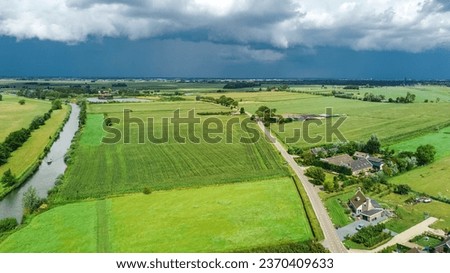 Aerial drone view of green fields and farm houses near canal from above, typical Dutch landscape, Holland, Netherlands
