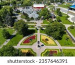 Aerial drone view of greenhouse and surrounding landscape at Chinguacousy Park in Brampton Ontario. Image features the clock circle flower beds and the red barn  of the petting zoo in the background.