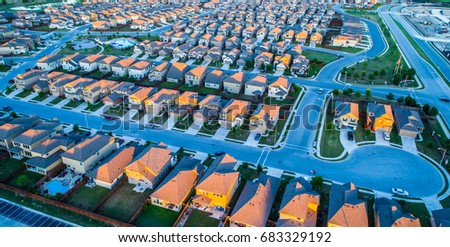 Aerial drone view high above rows and square cookie cutter houses in north Austin Texas near Round Rock , a growing suburb of ATX , with cup de sac and sunset colors on rooftop of suburbia