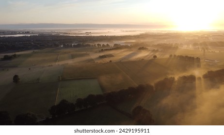 Aerial drone view of meadow landscape in The Netherlands on a sunny, foggy morning during golden hour. Misty low clouds, farmland landscape captured from above. - Powered by Shutterstock