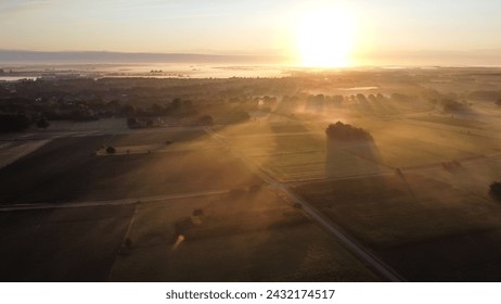 Aerial drone view of meadow landscape in The Netherlands on a sunny, foggy morning during golden hour. Misty low clouds farmland landscape captured from above. - Powered by Shutterstock