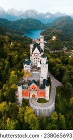 Aerial drone view Neuschwanstein castle on Alps background in vicinity of Munich, Bavaria, Germany, Europe. Autumn landscape with castle and lake in mountains covered with spruce forest