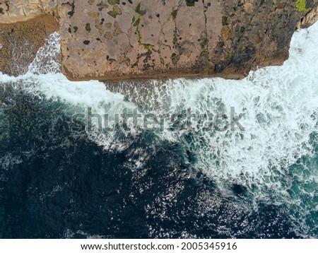 Aerial drone view on rough stone coast line of Inishmore, Aran islands, county Galway, Ireland. Blue ocean water with waves. Cloudy sky. Irish landscape. Top down view on the cliff