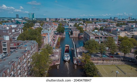 Aerial Drone View Of A Ship Passing Elevating Road Bridge In Amsterdam Canal. Ship Under Open Bridge Over The Canal.