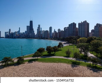 Aerial Drone View Of The Skyscraper Landscape Chicago Metropolitan Area During High Noon By Lake Michigan Beach Area.  Tourist And City Goers Alike Are Enjoying The Nice Weather And Colorful Buildings