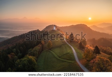 Aerial drone view of small beautiful church on top of a mountain in Slovenia at dawn. Beautiful autumn morning landscape