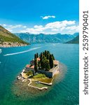 Aerial drone view of Sveti Dorde Island - Saint George Monastry in the middle of the island. In background is Perast city. Famous travel destination in Montenegro. Boats passing