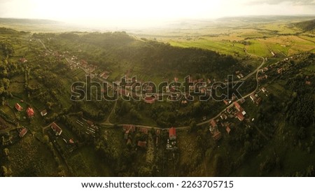 Aerial drone view of a village situated in a hilly region in Transylvania, Romania. Sunset time, countryside landscape, Romania.
