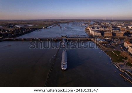 Aerial during extreme high water level of river IJssel in Zutphen, The Netherlands with cargo ships waiting for the steel draw bridge to let them pass. Aerial weather and climate concept.