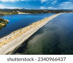 Aerial Esquimalt Lagoon sand spit overlooking Royal Roads University with a long straight road in Victoria British Columbia Canada.