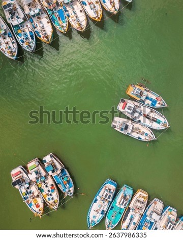 Aerial fly over view Tangalle Harbor on Sri Lanka southern coast, mix of fishing boats, catamarans, and small motor vessels anchored in calm turquoise waters. Fishing industry and tourism business