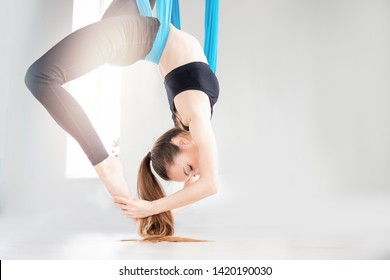 Aerial fly yoga young beautiful women gymnast in blue hammock. - Powered by Shutterstock