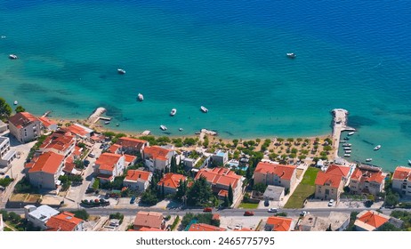 AERIAL: Flying above the beachfront real estate of Omis facing the breathtaking turquoise colored Adriatic sea. Drone shot of residential area of quaint coastal town with sandy beach and colorful sea. - Powered by Shutterstock