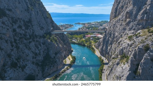 AERIAL: Flying above the gorge of Cetina river flowing out into the Adriatic sea, with a breathtaking panorama of the seafront city of Omis. Scenic view of the town of Omis on a sunny summer day. - Powered by Shutterstock